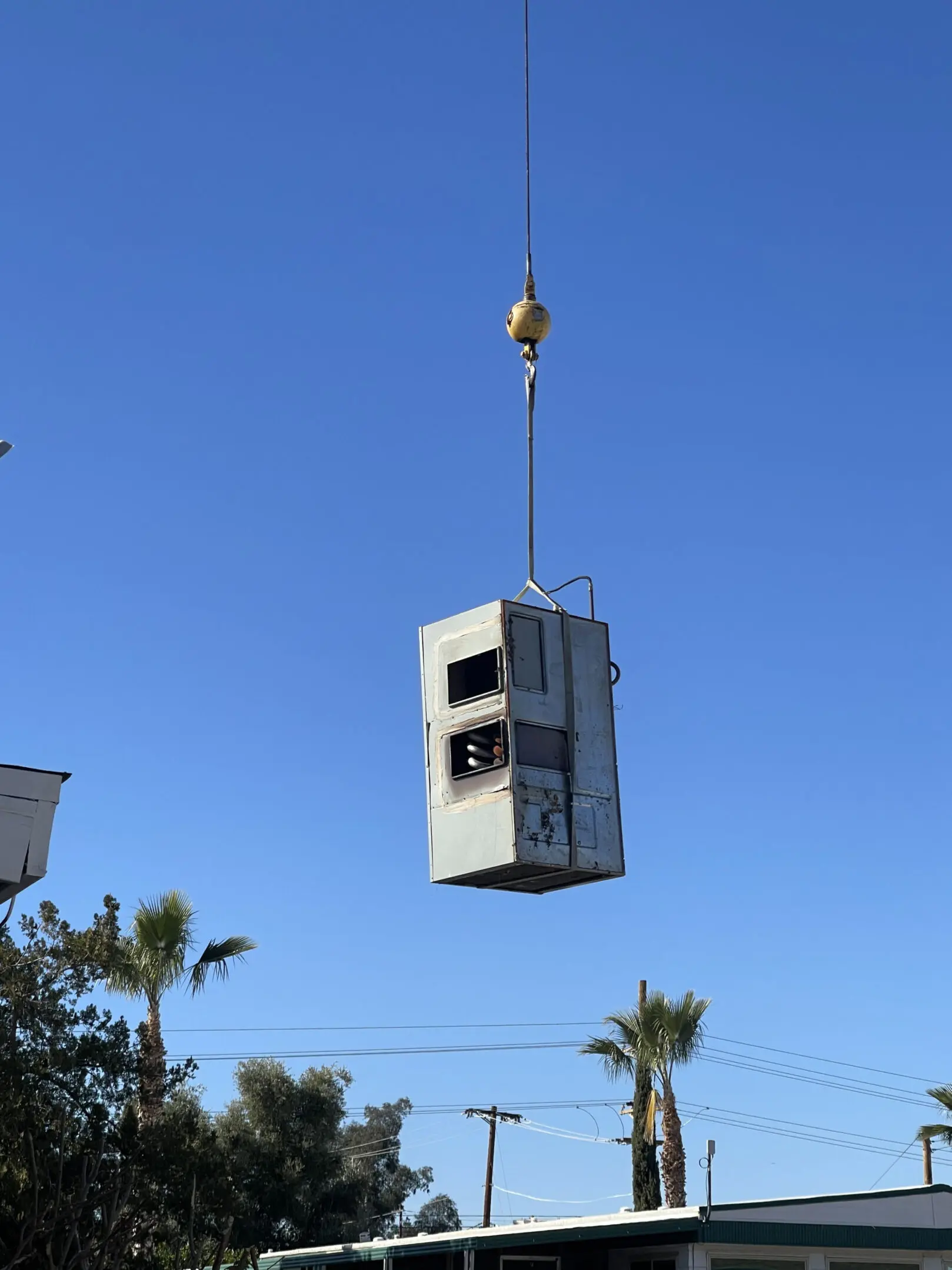 A crane is lifting a large box up to the sky.