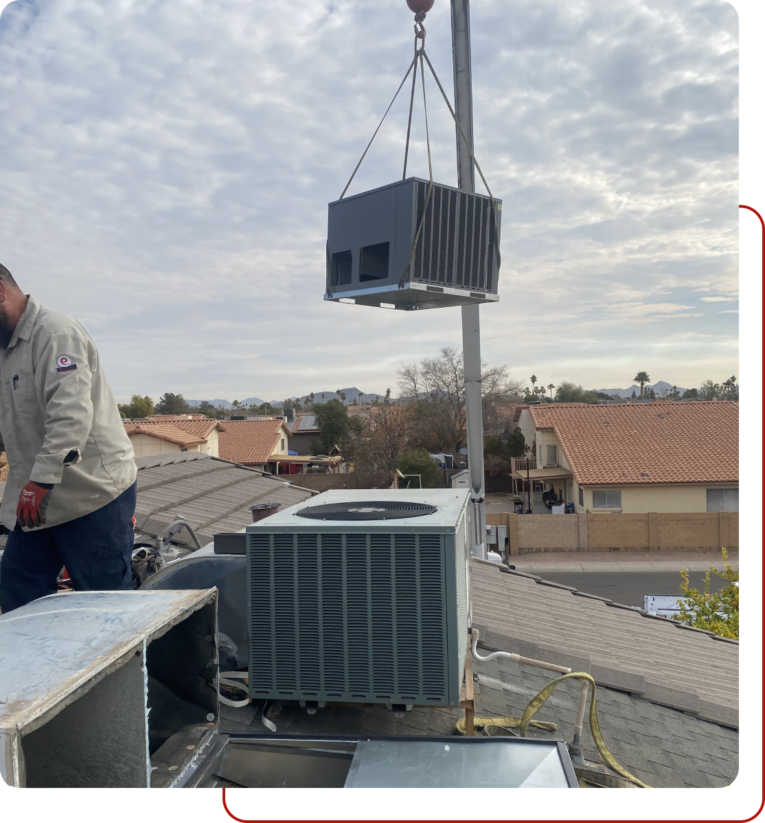 A man standing on top of a roof next to an air conditioner.